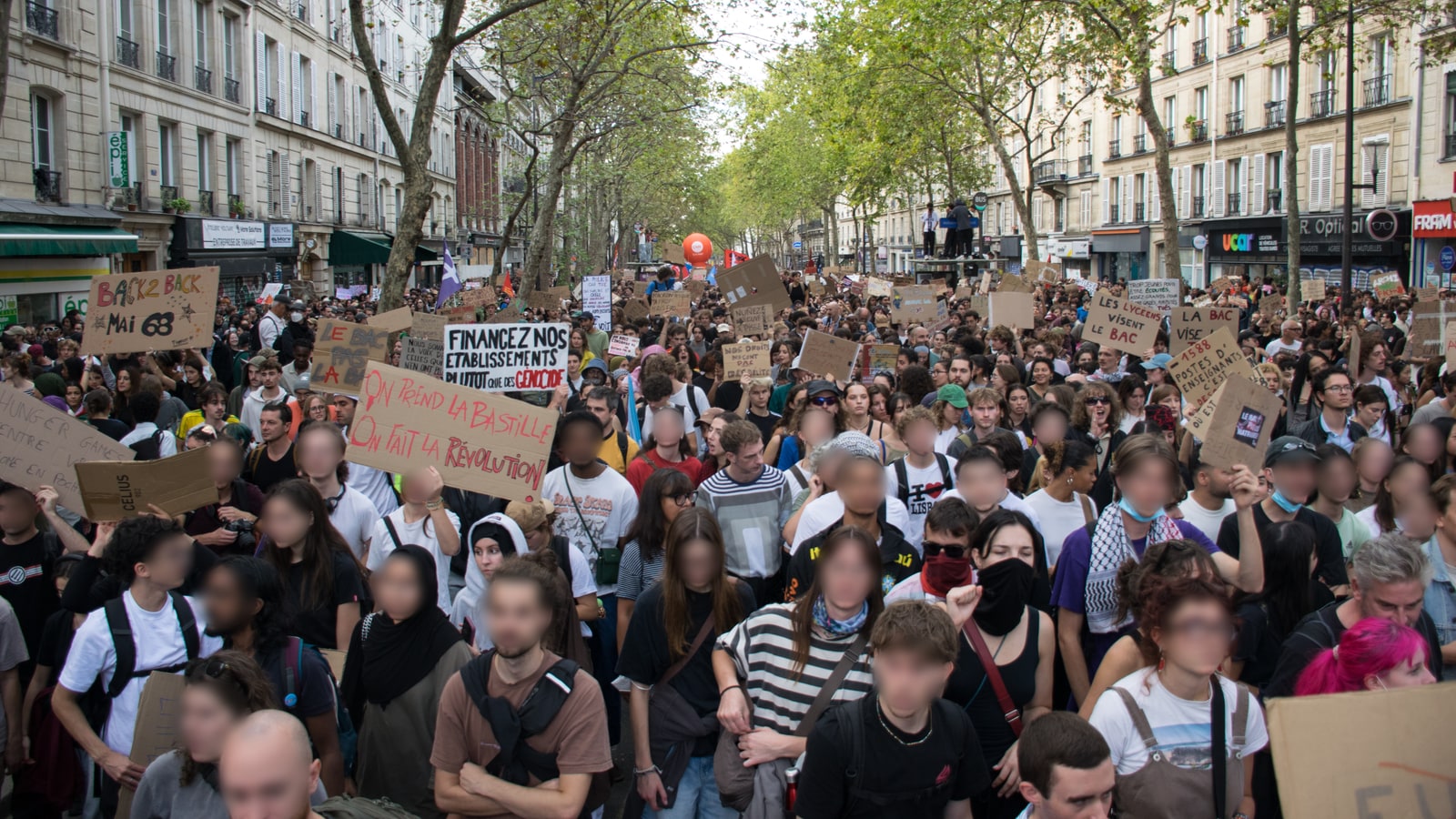 Le cortège de la manifestation lycéenne et étudiante du 6 octobre 2026 à Paris, entre République et Nation : une foule de jeunes avance sur un boulevard bordé d'arbres, pancartes en carton levées.